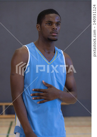 African american man athlete standing in gymnasium next to wooden bench showing painted court lines 140931124