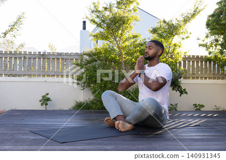 African American man sitting deck yoga mat meditating in gray sweats with watch, copy space African American man sitting deck yoga mat meditating in gray sweats with watch, copy space 140931345