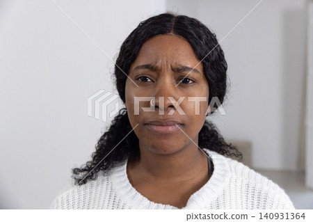 African American woman wearing white sweater, dark top, hoop nose ring, showing concern in room African American woman wearing white sweater, dark top, hoop nose ring, showing concern in room 140931364