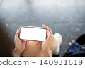 holding landscape smartphone mockup over her lap. 140931619