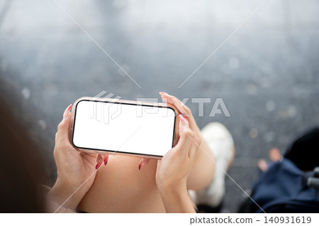 holding landscape smartphone mockup over her lap. holding landscape smartphone mockup over her lap. 140931619