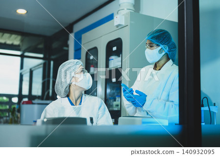 Two Female Scientists in Protective Gear Discussing Research Results in a Modern Laboratory Two Female Scientists in Protective Gear Discussing Research Results in a Modern Laboratory 140932095
