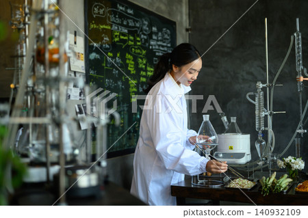 Young Asian Female Scientist in White Lab Coat Working with Distillation Equipment in Craft Beverage Laboratory 140932109