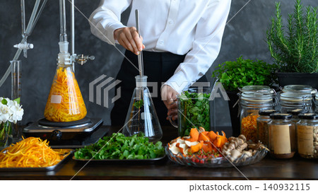 Food Scientist Using Laboratory Flask with Fresh Herbs, Spices, and Natural Ingredients on Wooden Table Food Scientist Using Laboratory Flask with Fresh Herbs, Spices, and Natural Ingredients on Wooden Table 140932115