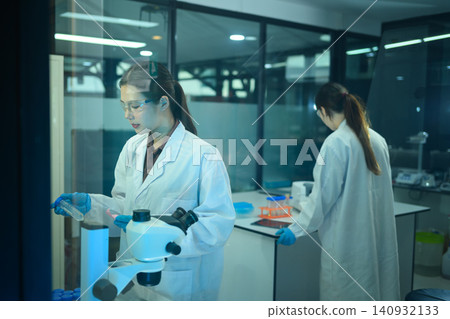 Two Asian Female Scientists Working in Modern Research Laboratory with Microscope and Test Tubes Two Asian Female Scientists Working in Modern Research Laboratory with Microscope and Test Tubes 140932133