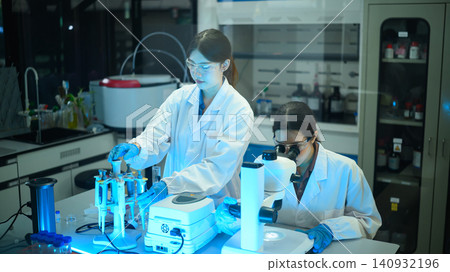 Two Asian Female Scientists Working Together in Modern Laboratory with Microscope and Pipette Equipment Two Asian Female Scientists Working Together in Modern Laboratory with Microscope and Pipette Equipment 140932196