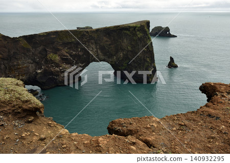 Massive stone arch of Dyrholaey peninsula rising from the sea, Iceland Massive stone arch of Dyrholaey peninsula rising from the sea, Iceland 140932295