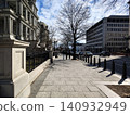 Washington Street with pedestrians strolling. On the left is a monumental historic building with columns; on the right are modern buildings. 140932949