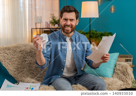 Young man frustrated and disappointed crumples a paper and throws it away while reviewing documents Young man frustrated and disappointed crumples a paper and throws it away while reviewing documents 140933010