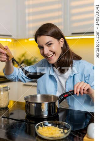 Young woman cooking healthy homemade soup in modern kitchen smiling during diet meal preparation fit 140933041