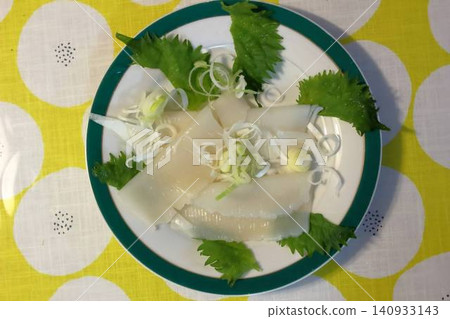 Squid sashimi served on a plate with a green rim, resembling somen noodles. Squid sashimi served on a plate with a green rim, resembling somen noodles. 140933143