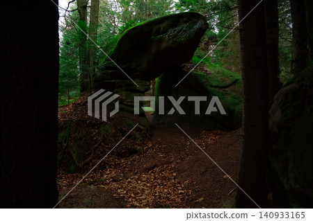 Spooky forest path leads through mossy rock formations at dusk Spooky forest path leads through mossy rock formations at dusk 140933165