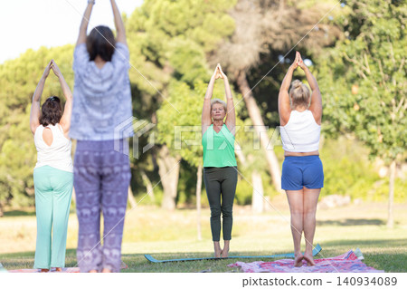 Mature women practicing yoga outdoors standing in mountain pose Mature women practicing yoga outdoors standing in mountain pose 140934089