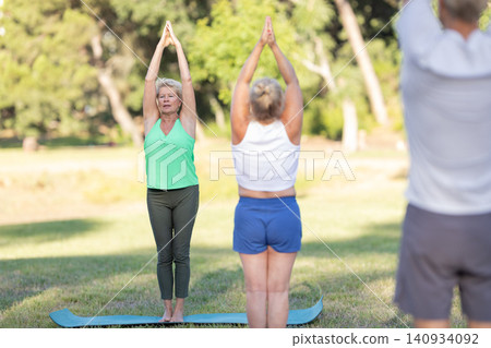 Seniors doing group yoga in park for wellness 140934092
