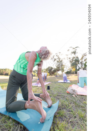 Senior woman practicing camel pose in outdoor yoga class 140934094