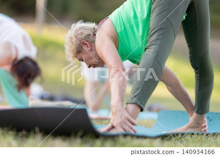 Older woman doing yoga exercise outdoor on mat Older woman doing yoga exercise outdoor on mat 140934166