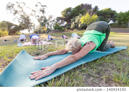 Senior women practicing outdoor yoga in child's pose Senior women practicing outdoor yoga in child's pose 140934193