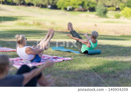 Senior women exercising boat pose during outdoor yoga class Senior women exercising boat pose during outdoor yoga class 140934209