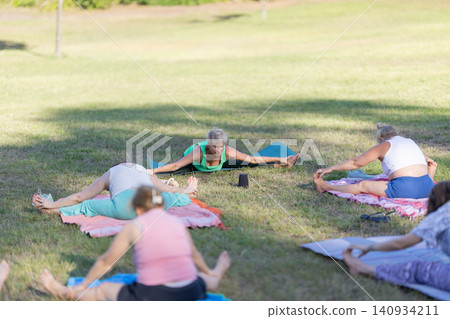 Women practicing yoga outdoors doing stretching exercises Women practicing yoga outdoors doing stretching exercises 140934211