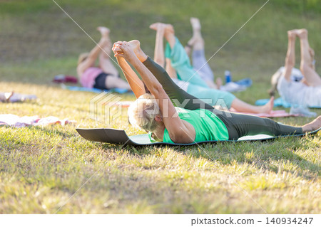 Senior women practicing yoga outdoors in a group class Senior women practicing yoga outdoors in a group class 140934247