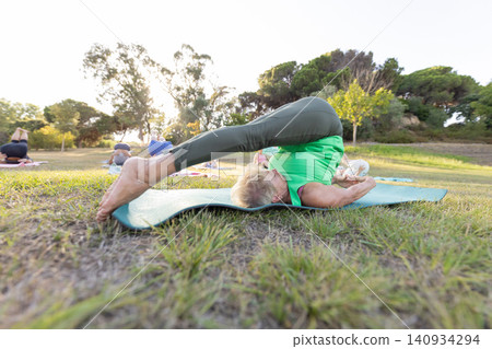 Senior woman practicing yoga plow pose outdoor Senior woman practicing yoga plow pose outdoor 140934294
