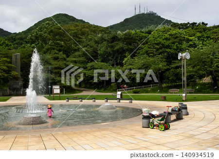 [Child's face hidden by hat] Girl playing in a fountain at Hakodate Park, Hakodate City 140934519