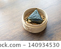 Close-up of traditional Japanese onigiri rice ball served in a natural bamboo bowl 140934530