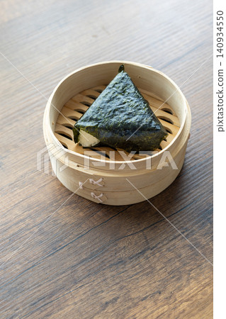 Close-up of traditional Japanese onigiri rice ball served in a natural bamboo bowl 140934550