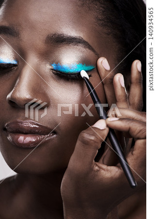 Brush, makeup and face of black woman with cosmetics for wellness, beauty and model. Cosmetology, skincare and person with tools for makeover application, blue eyeshadow and products in studio 140934565