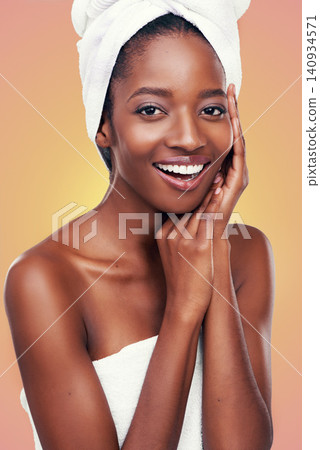 Hair towel, portrait and black woman in studio for skincare, wellness or body care on orange background. Beauty, cleaning or hands on face of African female model with cosmetic, shine or glowing skin Hair towel, portrait and black woman in studio for skincare, wellness or body care on orange background. Beauty, cleaning or hands on face of African female model with cosmetic, shine or glowing skin 140934571