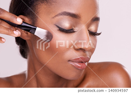 Beauty, makeup and black woman with brush on face in studio with cosmetic application tool. Skincare, blush and cosmetics, facial skin care model with luxury contour powder product on pink background Beauty, makeup and black woman with brush on face in studio with cosmetic application tool. Skincare, blush and cosmetics, facial skin care model with luxury contour powder product on pink background 140934597