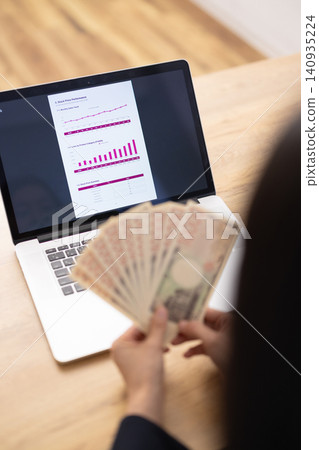A close-up of a woman's hands as she counts out 10,000 yen bills. A close-up of a woman's hands as she counts out 10,000 yen bills. 140935224