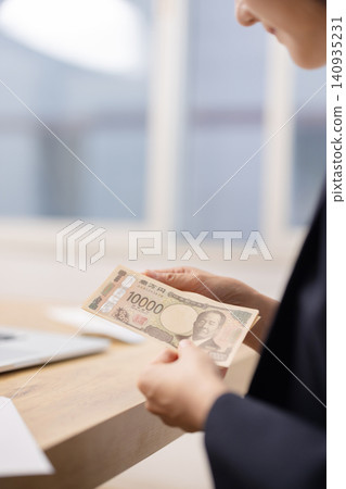 特寫鏡頭拍攝一位女士數著10000日元鈔票的手。 140935231
