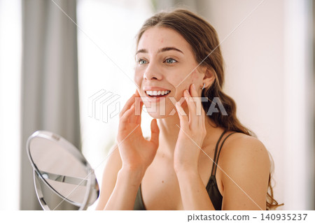 Young woman with problem skin looking into mirror. Inflammation on face, problem skin. Beauty care. Young woman with problem skin looking into mirror. Inflammation on face, problem skin. Beauty care. 140935237
