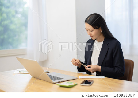 A woman spreads out 10,000 yen bills on her desk and counts them. A woman spreads out 10,000 yen bills on her desk and counts them. 140935397