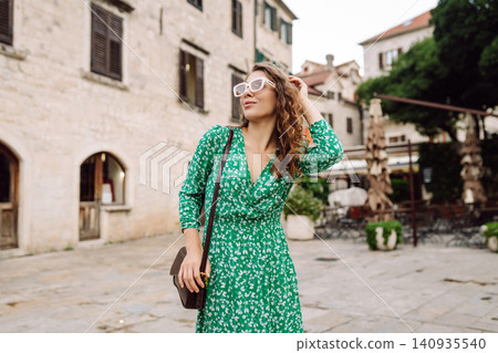 Happy female tourist in beautiful dress walking in the street of the city. Fashion style. Happy female tourist in beautiful dress walking in the street of the city. Fashion style. 140935540