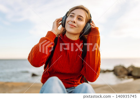 Relaxed woman enjoying music by the waterfront while wearing headphone. Travel and blogging concept Relaxed woman enjoying music by the waterfront while wearing headphone. Travel and blogging concept 140935745