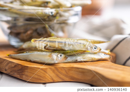 Fresh Whitebait Small Fish Stack on Wooden Board With Glass Bowl of Seafood Fresh Whitebait Small Fish Stack on Wooden Board With Glass Bowl of Seafood 140936140