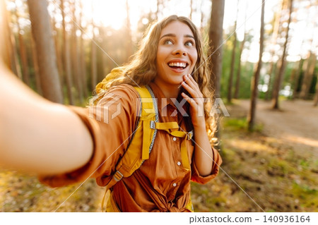 Selfie in nature. Beautiful woman taking picture of herself while walking in a sunny forest. Selfie in nature. Beautiful woman taking picture of herself while walking in a sunny forest. 140936164