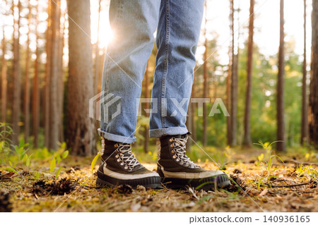 Feet of an adult wearing boots to travel walking in a green forest. Travel and hiking. 140936165