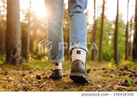 Feet of an adult wearing boots to travel walking in a green forest. Travel and hiking. Feet of an adult wearing boots to travel walking in a green forest. Travel and hiking. 140936166