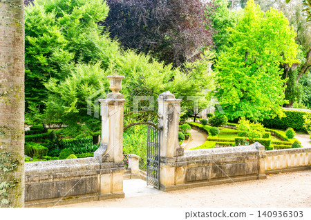 An elegant stone gateway with an ornate iron gate opens into a lush, manicured historic garden, perfect for themes of discovery, elegance, romance, and classic landscape design. An elegant stone gateway with an ornate iron gate opens into a lush, manicured historic garden, perfect for themes of discovery, elegance, romance, and classic landscape design. 140936303