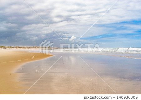 A serene, vast sandy beach under a dramatic cloudy sky evokes a sense of peaceful solitude. This beautiful coastal landscape with nobody is perfect for travel or wellness backgrounds. A serene, vast sandy beach under a dramatic cloudy sky evokes a sense of peaceful solitude. This beautiful coastal landscape with nobody is perfect for travel or wellness backgrounds. 140936309