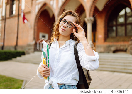 Woman student with curly hair standing outside a historic university. University Student On Campus 140936345