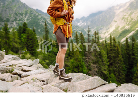 Female legs in hiking boots on hiking trail, on top of mountain outdoors. Nature, relaxation concept Female legs in hiking boots on hiking trail, on top of mountain outdoors. Nature, relaxation concept 140936619