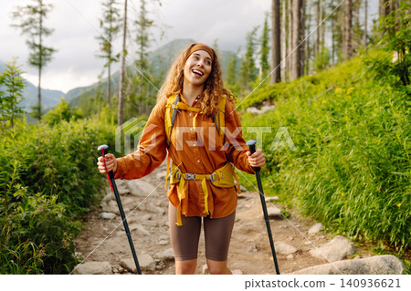 Woman travels along hiking trails among mountains with yellow backpack and hiking boots. Vacation. Woman travels along hiking trails among mountains with yellow backpack and hiking boots. Vacation. 140936621