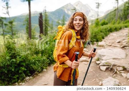 Woman travels along hiking trails among mountains with yellow backpack and hiking boots. Vacation. Woman travels along hiking trails among mountains with yellow backpack and hiking boots. Vacation. 140936624