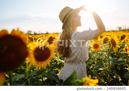 Woman strolling through field with sunflowers. Fashion, lifestyle, travel and vacations concept. Woman strolling through field with sunflowers. Fashion, lifestyle, travel and vacations concept. 140936695