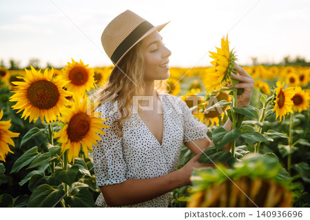 Woman strolling through field with sunflowers. Fashion, lifestyle, travel and vacations concept. Woman strolling through field with sunflowers. Fashion, lifestyle, travel and vacations concept. 140936696