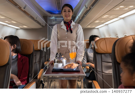 Airplane flight attendant serving food and drink to passengers in cabin. Airplane flight attendant serving food and drink to passengers in cabin. 140937277